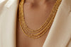 Gold necklace worn by a person with a blurred background